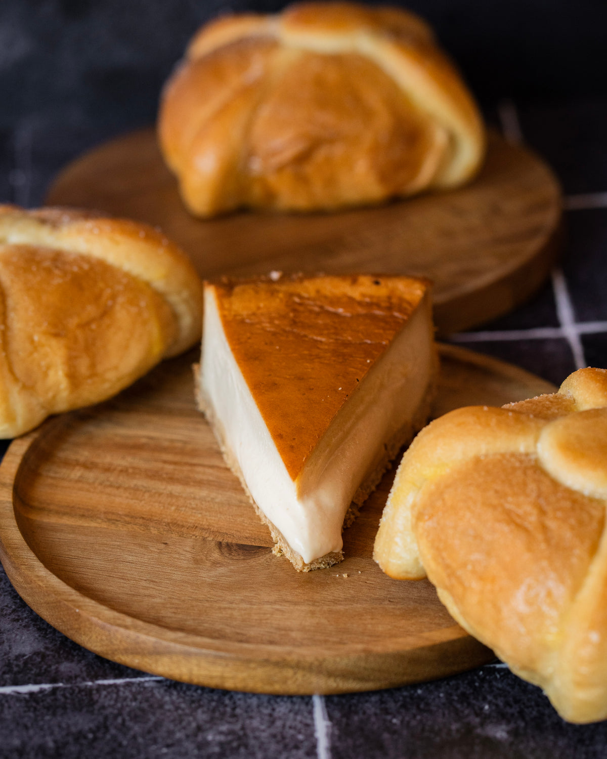 Rebanada de tarta de queso y pan de muerto rodeado de panes